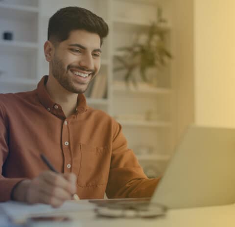 Homen feliz trabalhando em seu laptop.