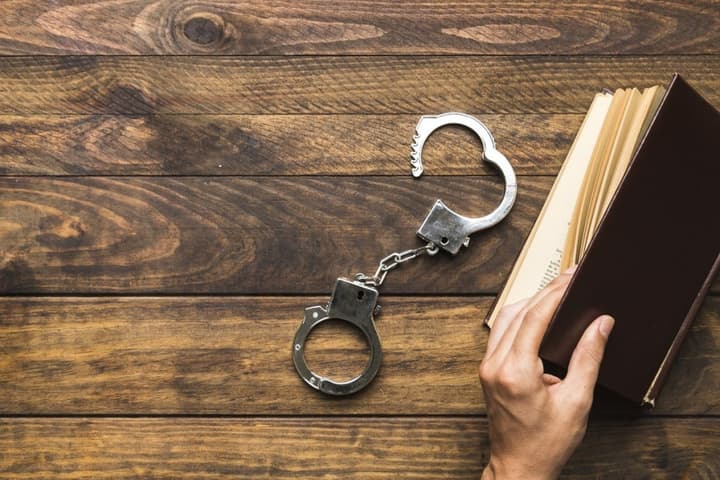 Algema para prisão preventiva ao lado de livro (Foto: Freepik)